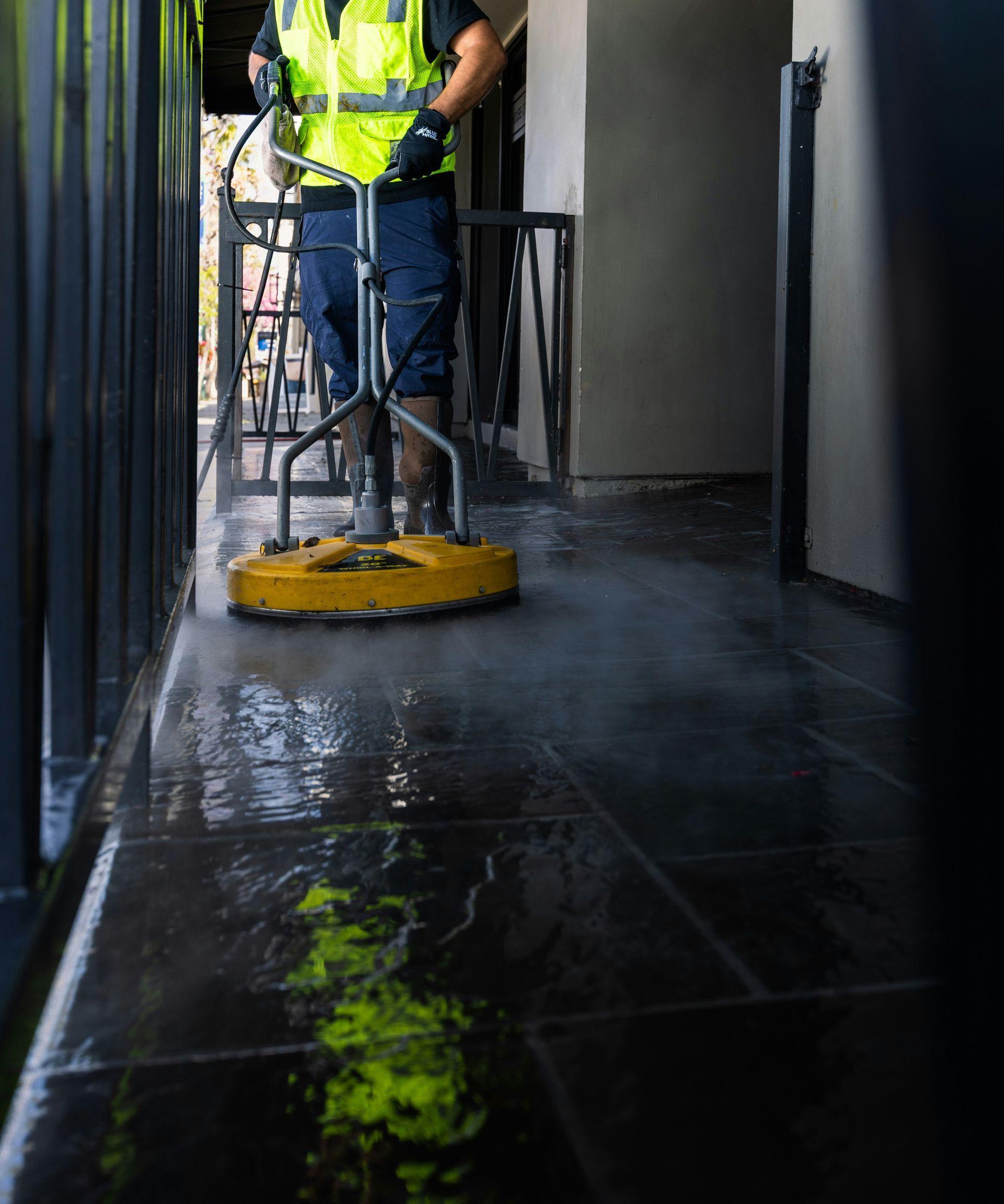 a man in a yellow vest is cleaning the floor
